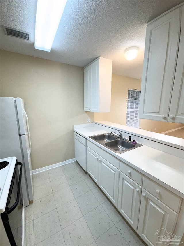 kitchen featuring sink, a textured ceiling, white cabinets, and white appliances