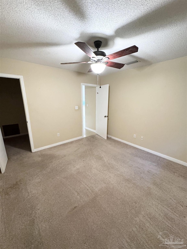 empty room featuring ceiling fan, light carpet, and a textured ceiling