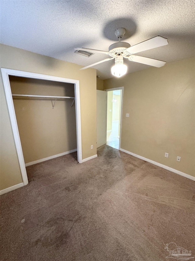 unfurnished bedroom with a textured ceiling, carpet floors, a closet, and ceiling fan