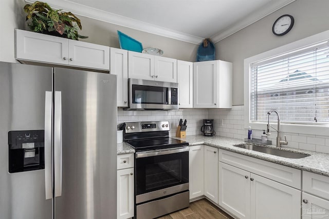 kitchen featuring a sink, white cabinets, appliances with stainless steel finishes, tasteful backsplash, and crown molding