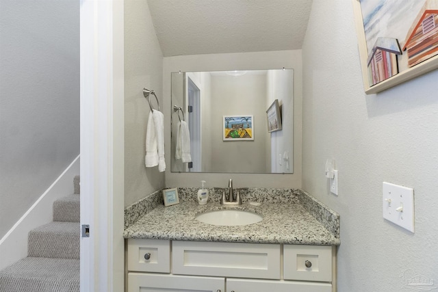 bathroom with a textured wall, a textured ceiling, and vanity