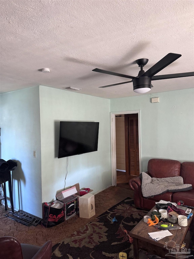 carpeted living room featuring visible vents, a textured ceiling, and a ceiling fan