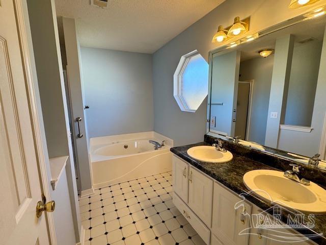 bathroom with separate shower and tub, vanity, and a textured ceiling