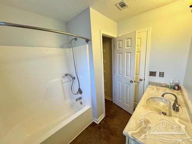 bathroom featuring vanity, a textured ceiling, and washtub / shower combination