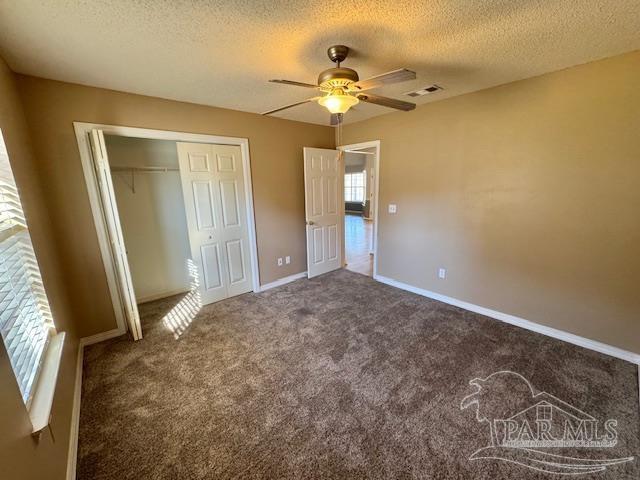 unfurnished bedroom featuring carpet flooring, ceiling fan, a closet, and a textured ceiling