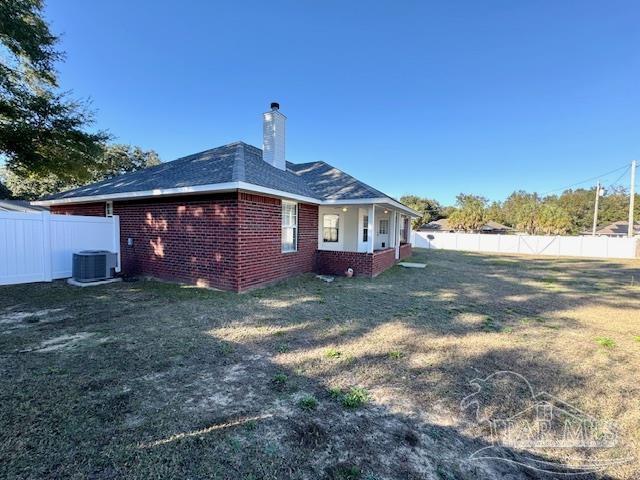 rear view of house featuring a yard and central AC unit