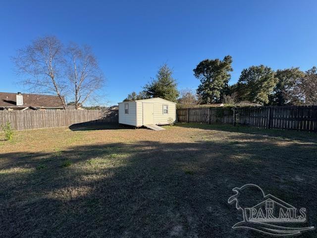 view of yard featuring an outbuilding, a fenced backyard, and a shed