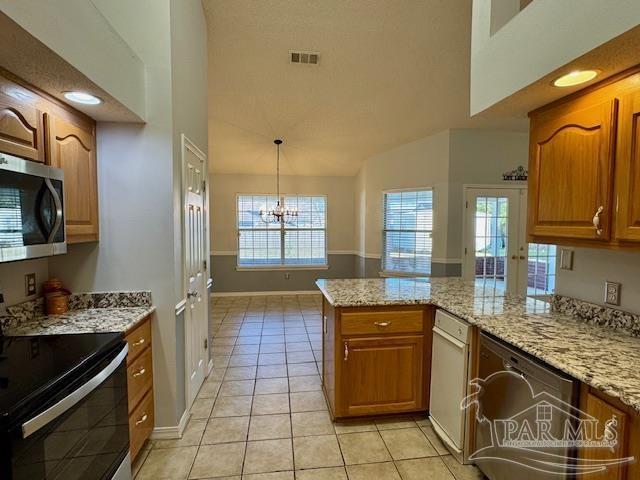 kitchen featuring pendant lighting, light tile patterned floors, kitchen peninsula, stainless steel appliances, and a chandelier