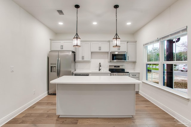 kitchen with a sink, tasteful backsplash, a center island, appliances with stainless steel finishes, and light countertops