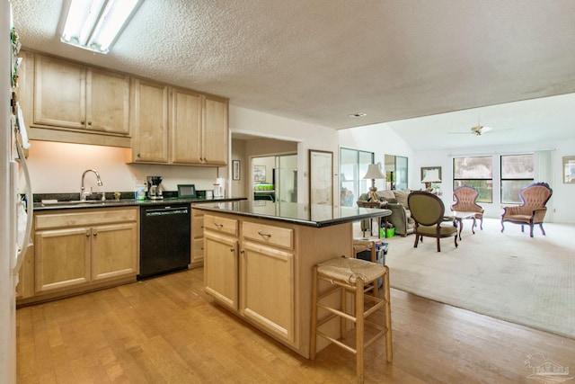 kitchen with black dishwasher, dark countertops, open floor plan, light brown cabinetry, and a sink