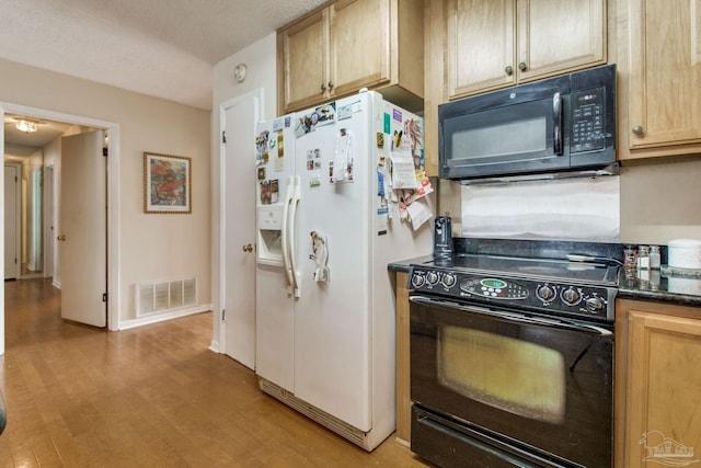 kitchen with dark countertops, visible vents, light wood-style flooring, black appliances, and baseboards