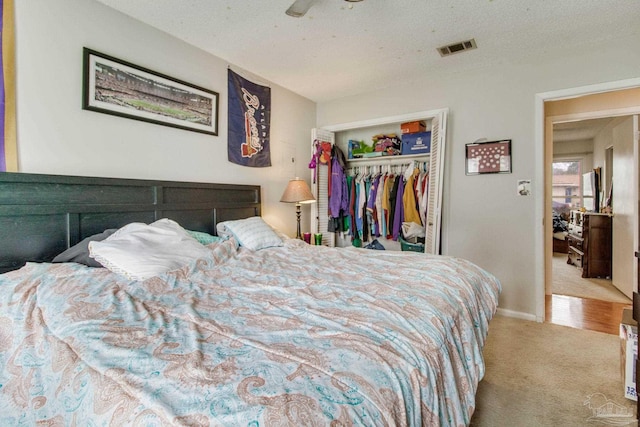 bedroom featuring a textured ceiling, carpet floors, a closet, and visible vents