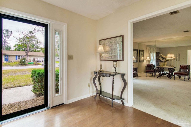 foyer with visible vents, baseboards, and wood finished floors