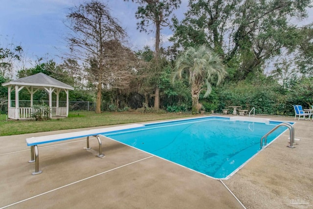 outdoor pool with a patio, a lawn, a gazebo, fence, and a diving board