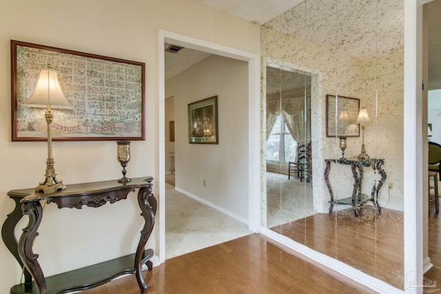 corridor featuring wood finished floors, visible vents, and baseboards