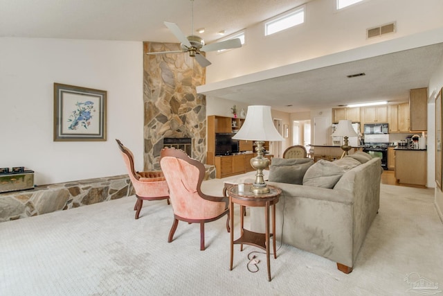 living room featuring light carpet, a high ceiling, visible vents, and a stone fireplace