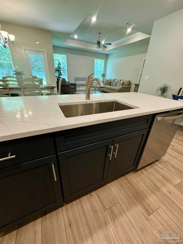 kitchen featuring light stone counters, a raised ceiling, and sink