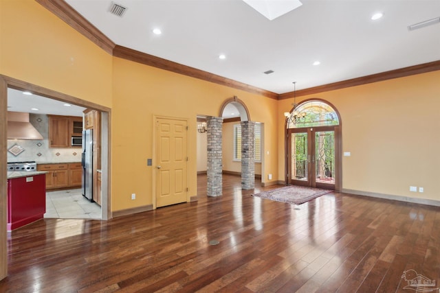 unfurnished living room featuring crown molding, dark hardwood / wood-style floors, a skylight, and french doors