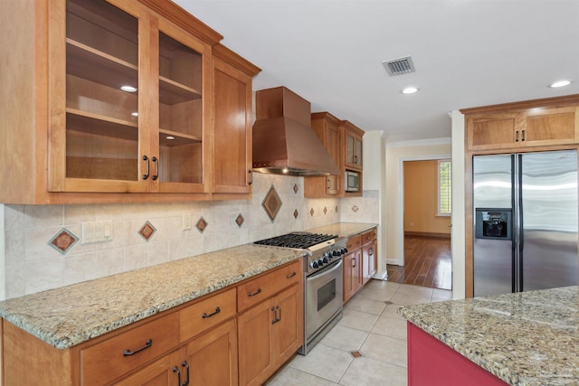 kitchen featuring light stone counters, light tile patterned flooring, stainless steel appliances, and premium range hood