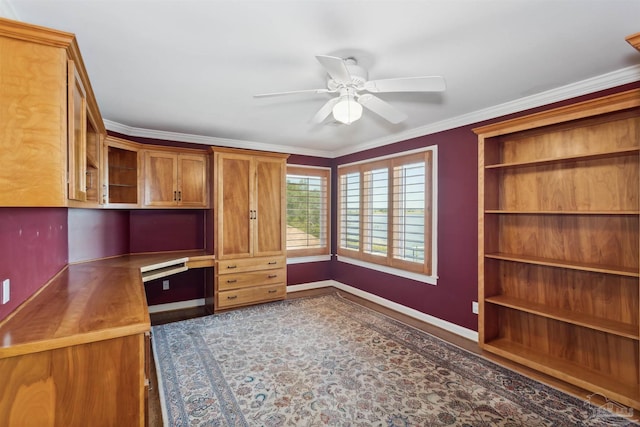 unfurnished office with crown molding, built in desk, and ceiling fan