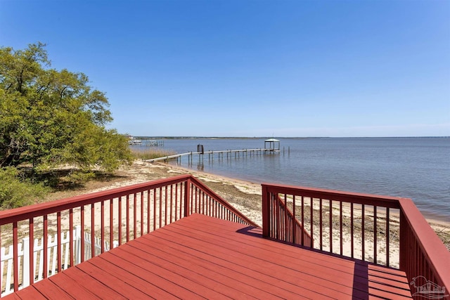 deck with a water view, a beach view, and a boat dock