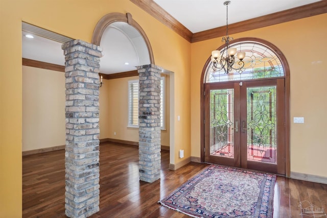 entryway featuring decorative columns, ornamental molding, dark hardwood / wood-style flooring, french doors, and a chandelier