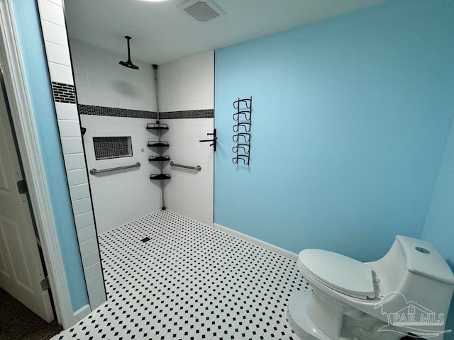 bathroom with toilet, tile patterned floors, and a tile shower