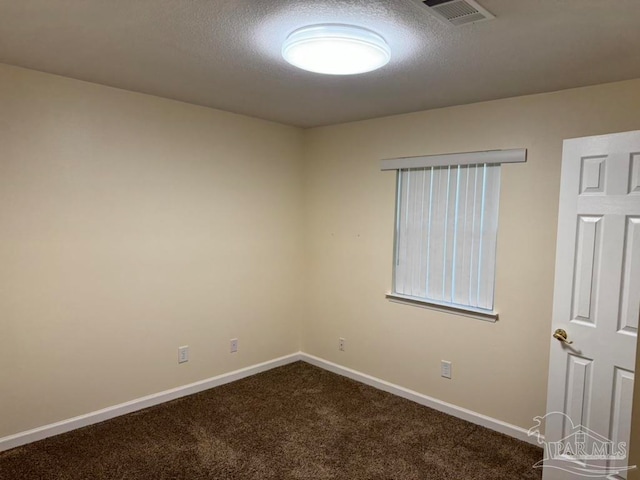 carpeted empty room featuring a textured ceiling