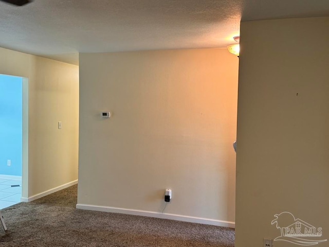 carpeted empty room featuring a textured ceiling