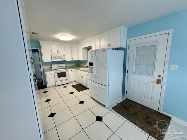 kitchen featuring white appliances, sink, light tile patterned floors, and white cabinets