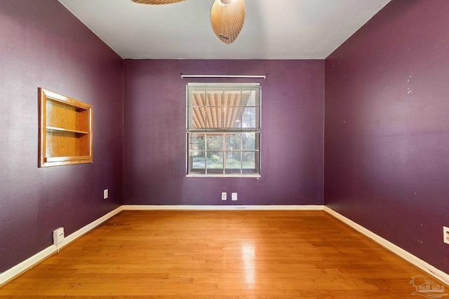 empty room featuring hardwood / wood-style flooring, built in shelves, and ceiling fan