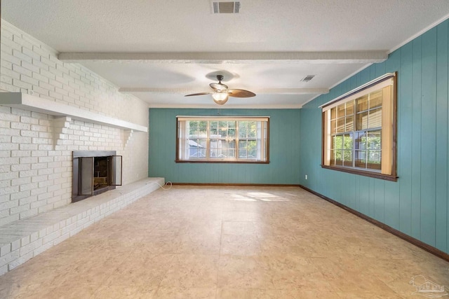 unfurnished living room with a fireplace, beam ceiling, and a textured ceiling