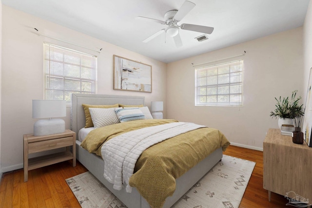 bedroom featuring ceiling fan, dark wood-type flooring, and multiple windows