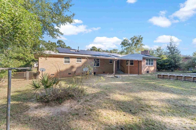 back of house featuring a yard and solar panels