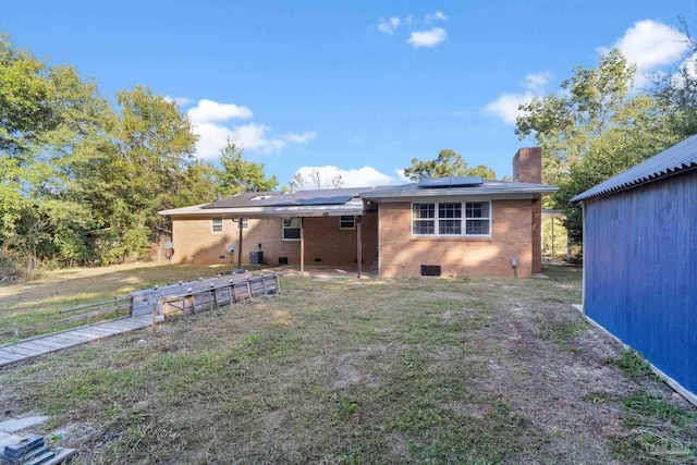 rear view of house with solar panels and a yard