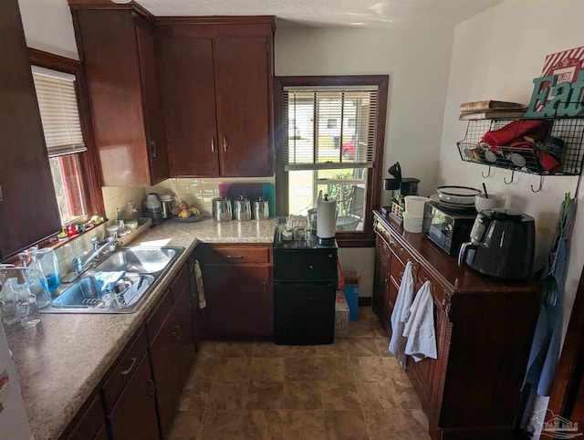 kitchen with a sink, tasteful backsplash, black microwave, and light countertops