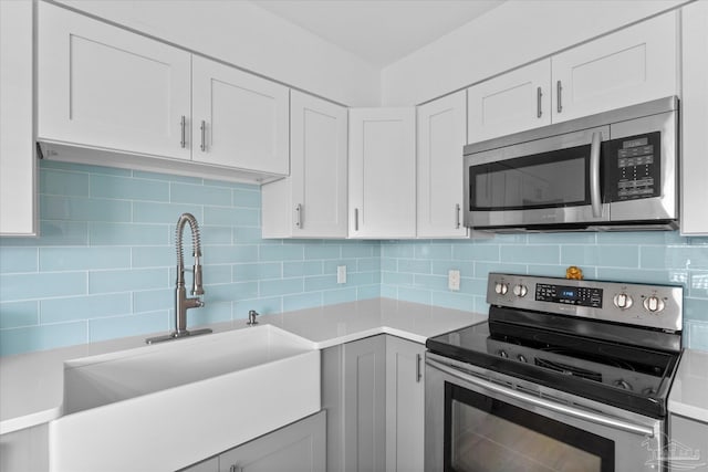 kitchen featuring stainless steel appliances, white cabinets, and tasteful backsplash