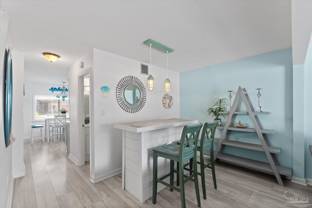 bar with hanging light fixtures and light hardwood / wood-style flooring