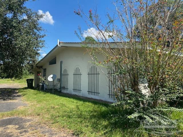 view of side of property with a yard and central AC