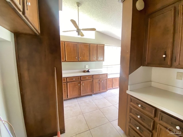 kitchen featuring a textured ceiling, light tile patterned flooring, vaulted ceiling, and ceiling fan