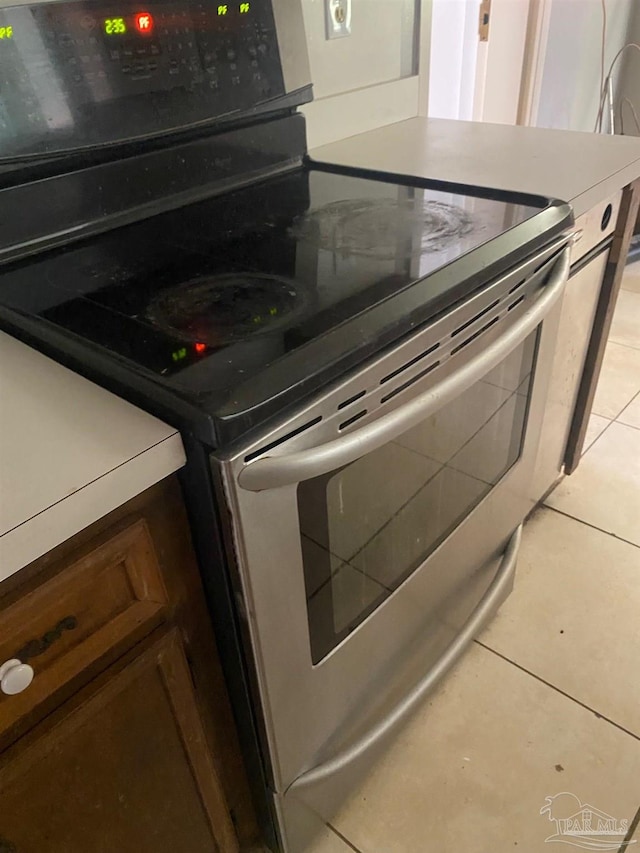 details with electric stove and light tile patterned flooring