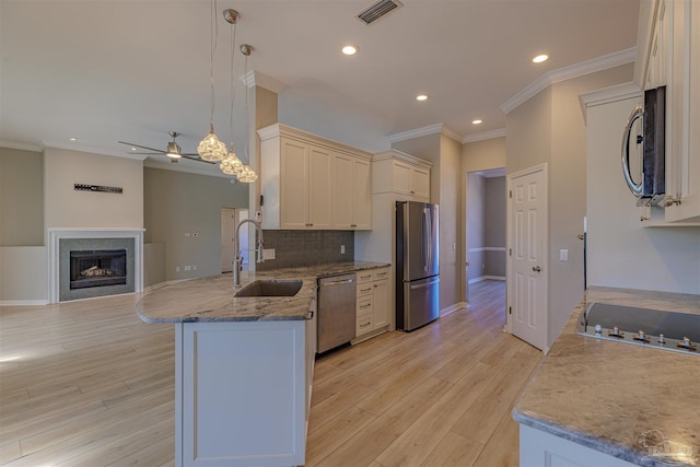 kitchen featuring stainless steel appliances, a fireplace, a sink, visible vents, and decorative light fixtures