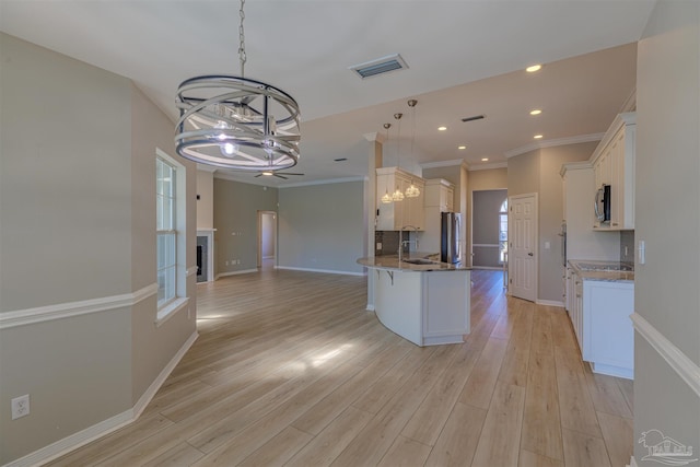 kitchen with a notable chandelier, stainless steel appliances, visible vents, white cabinetry, and a peninsula