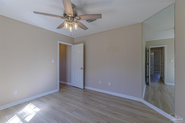 empty room with ceiling fan, light wood-style flooring, and baseboards