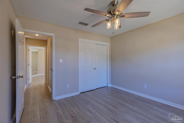 unfurnished bedroom featuring ceiling fan, light wood-style flooring, visible vents, baseboards, and a closet