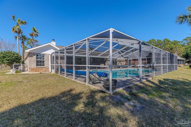 outdoor pool featuring glass enclosure, a lawn, and a patio