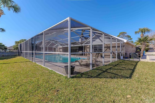 pool featuring glass enclosure, a patio area, and a lawn