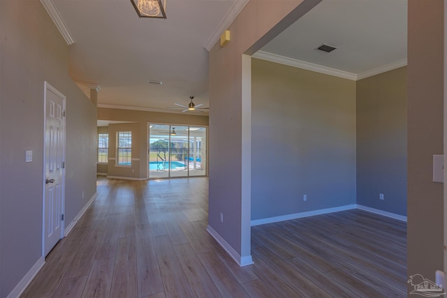 corridor with ornamental molding, light wood-style flooring, and visible vents