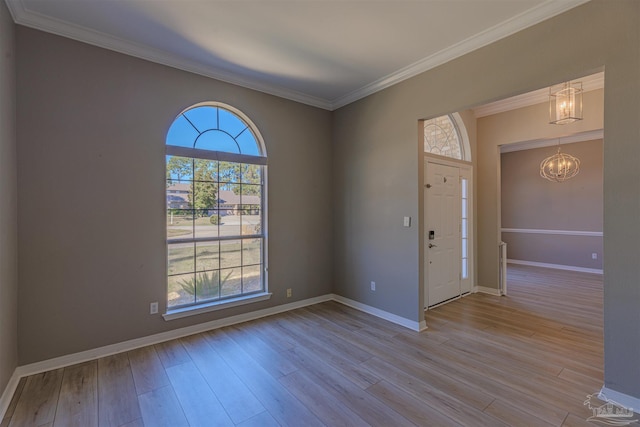 entryway with crown molding, light wood-style flooring, baseboards, and an inviting chandelier