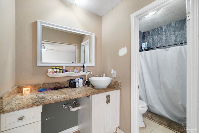 bathroom with a textured ceiling, vanity, ceiling fan, tile patterned flooring, and toilet